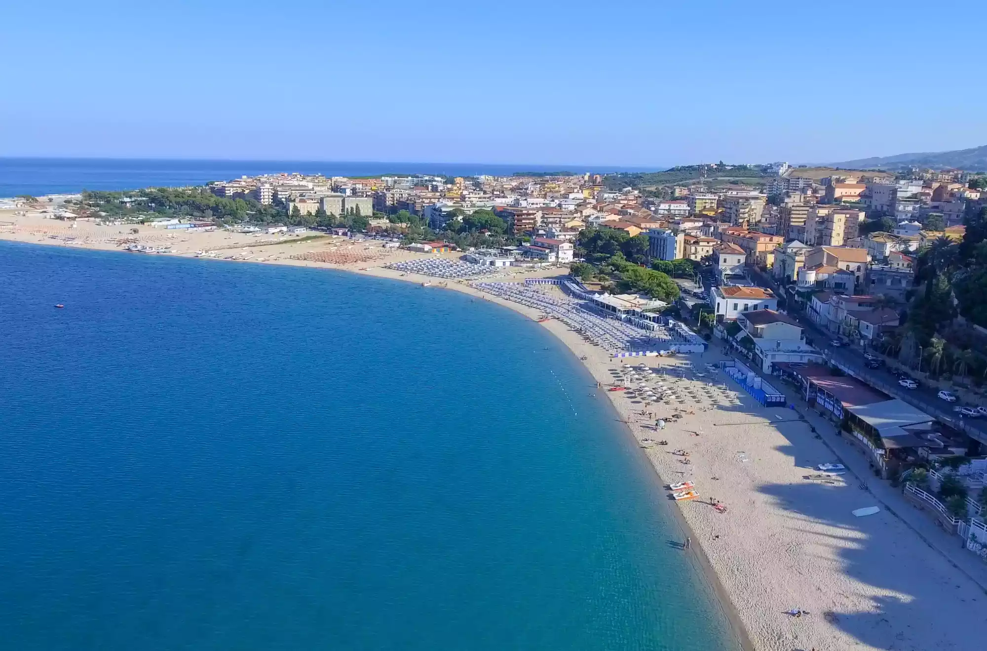 Lunga spiaggia sabbiosa sulla Costa Ionica della Calabria con mare calmo e lungomare urbano