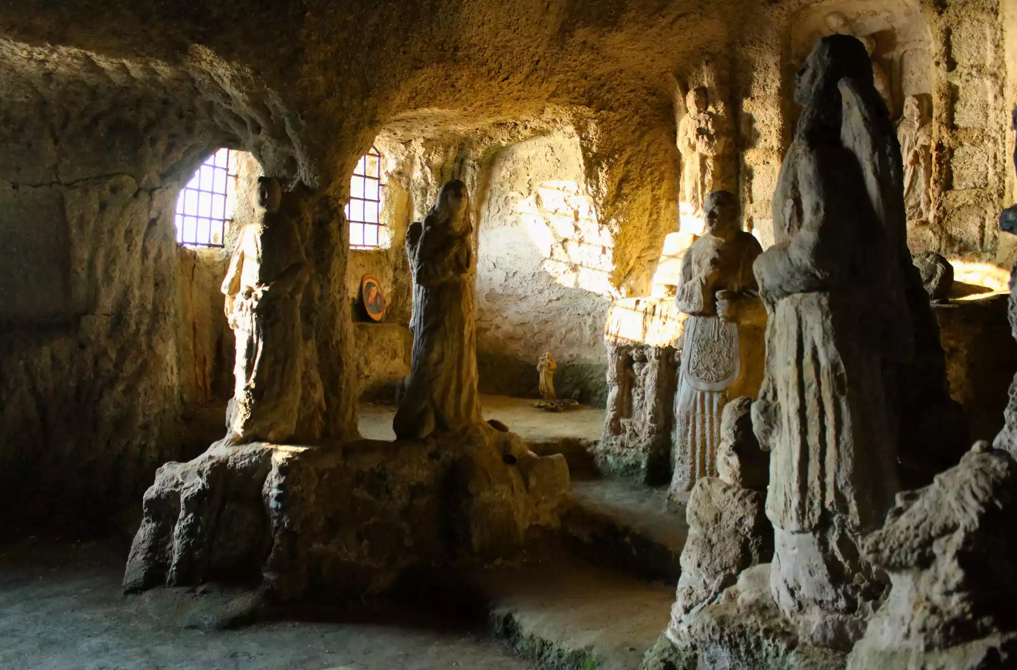 Interno della chiesetta di Piedigrotta a Pizzo Calabro, con statue scolpite nella roccia illuminate dalla luce naturale