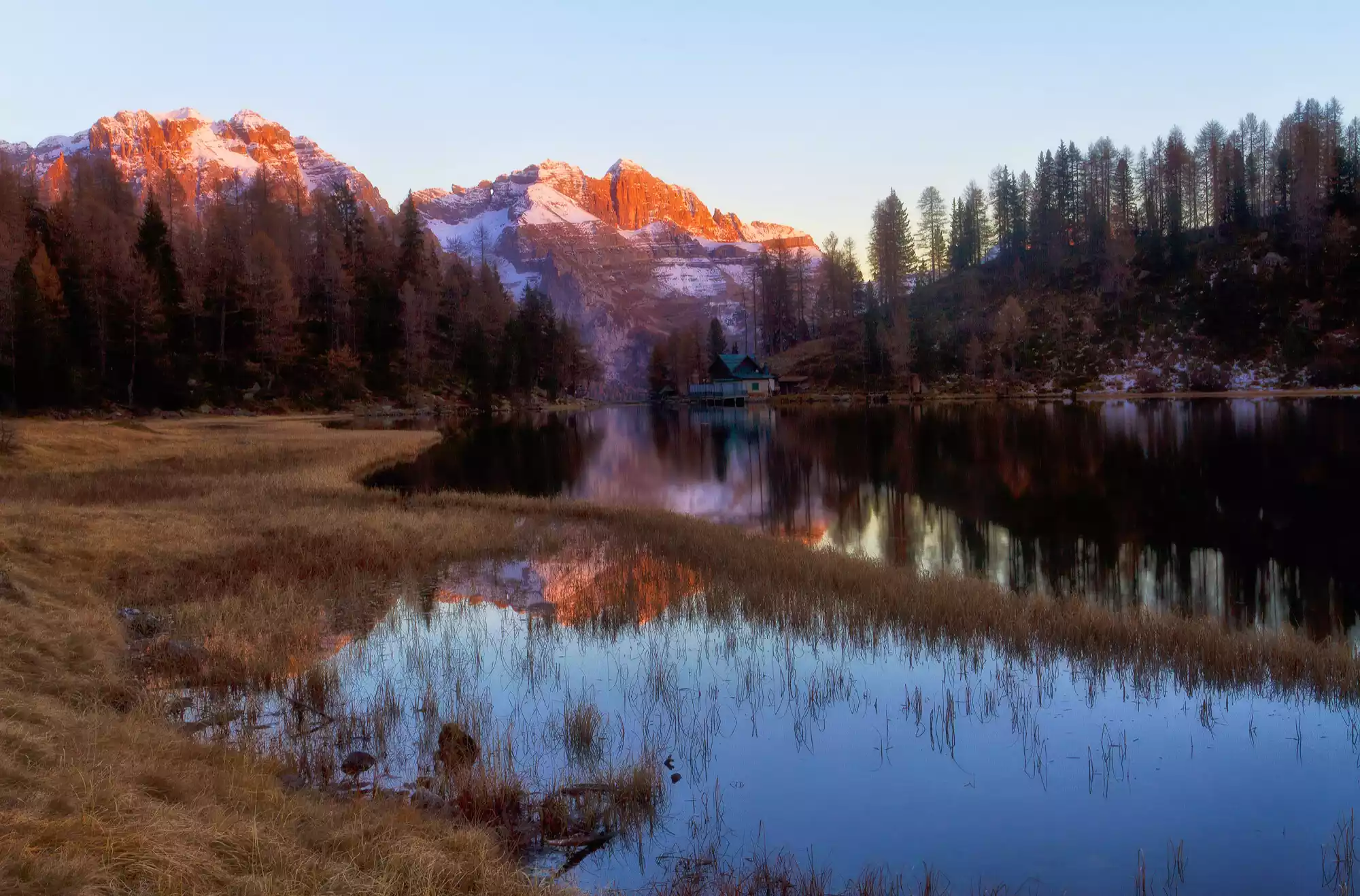 Lago delle Malghette in Trentino, foto di un'escursione in montagna con il riflesso delle vette dolomitiche e la pineta sulle acque del lago alpino.