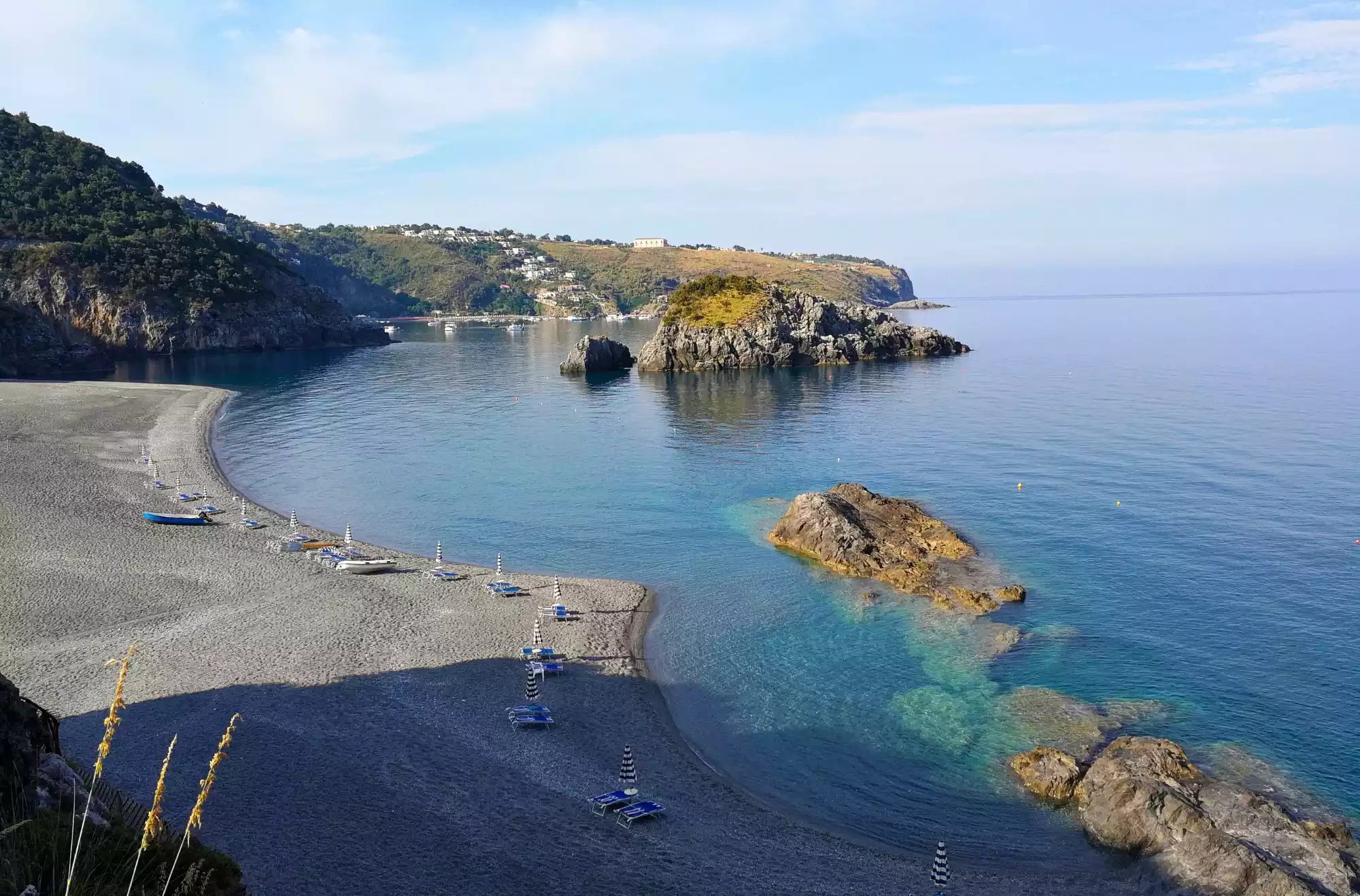 Spiaggia dello Scorzone vista dall’alto, con sabbia scura, scogli affioranti e mare cristallino sulla costa calabrese