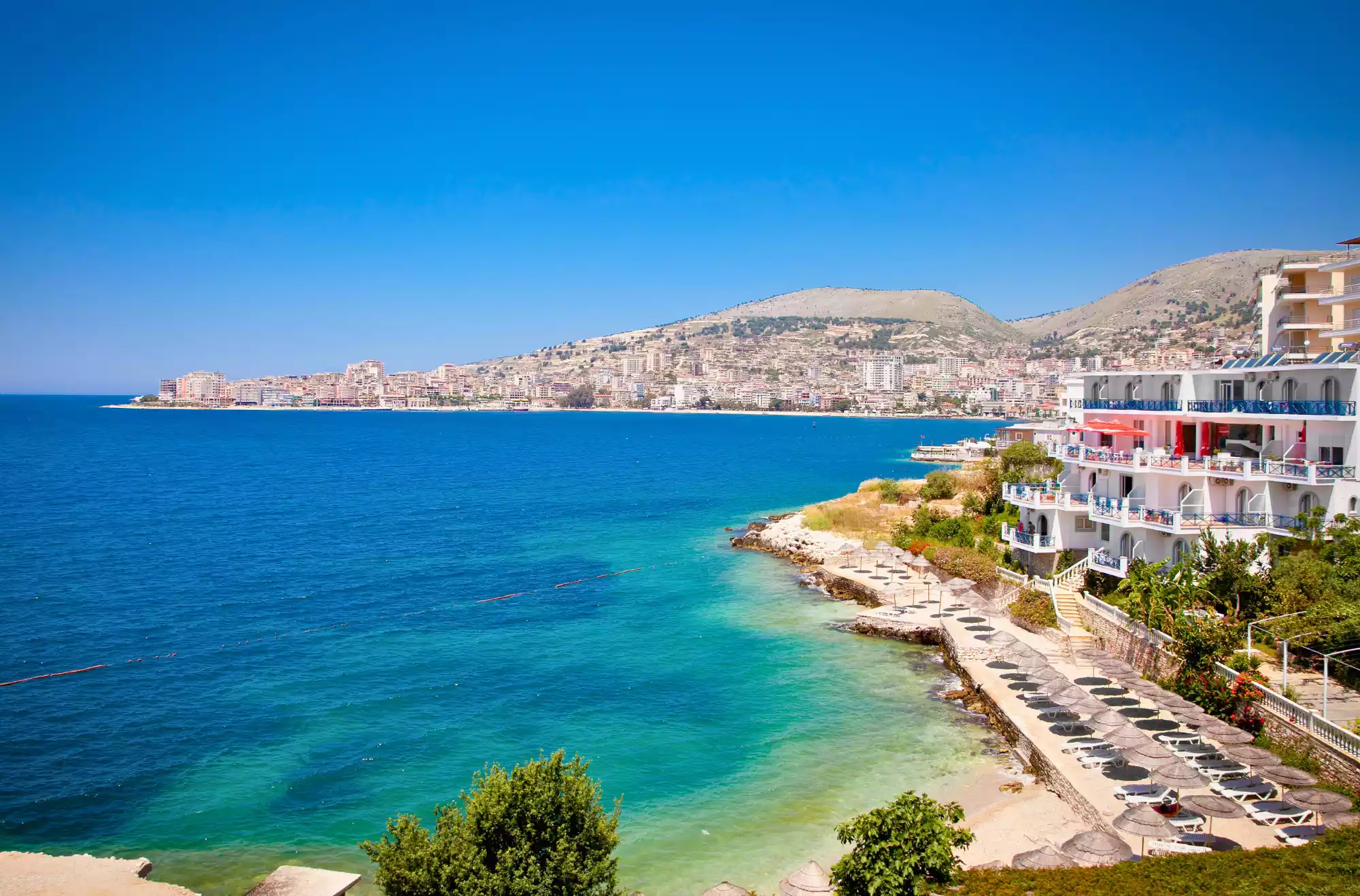 Saranda - in Albania - vista panoramica sulla costa che si affaccia su un mare dai colori blu e turchesi in una splendida giornata soleggiata.