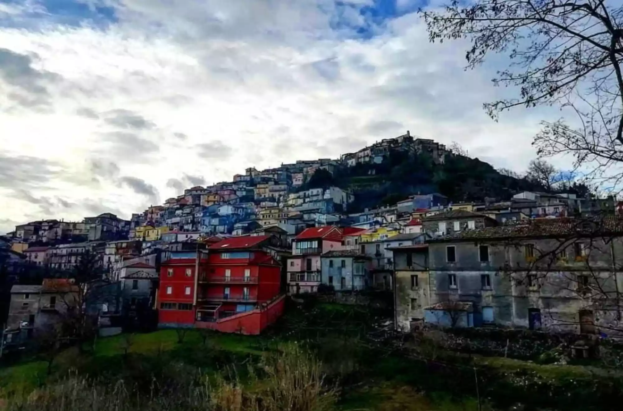 Panorama del borgo collinare di Tiriolo in Calabria, con case colorate disposte sul pendio e cielo nuvoloso