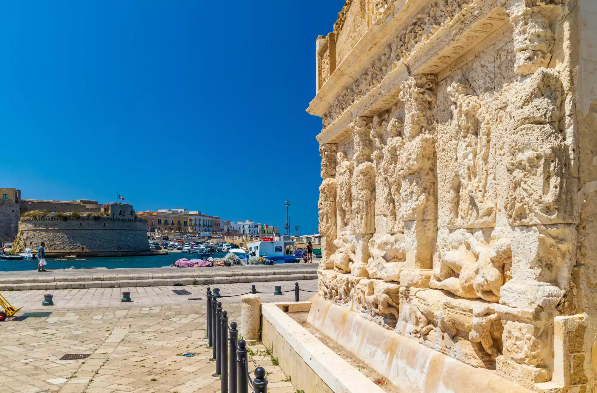 Fontana Greca di Gallipoli con rilievi scolpiti in pietra, vista sul porto e sul Castello Angioino