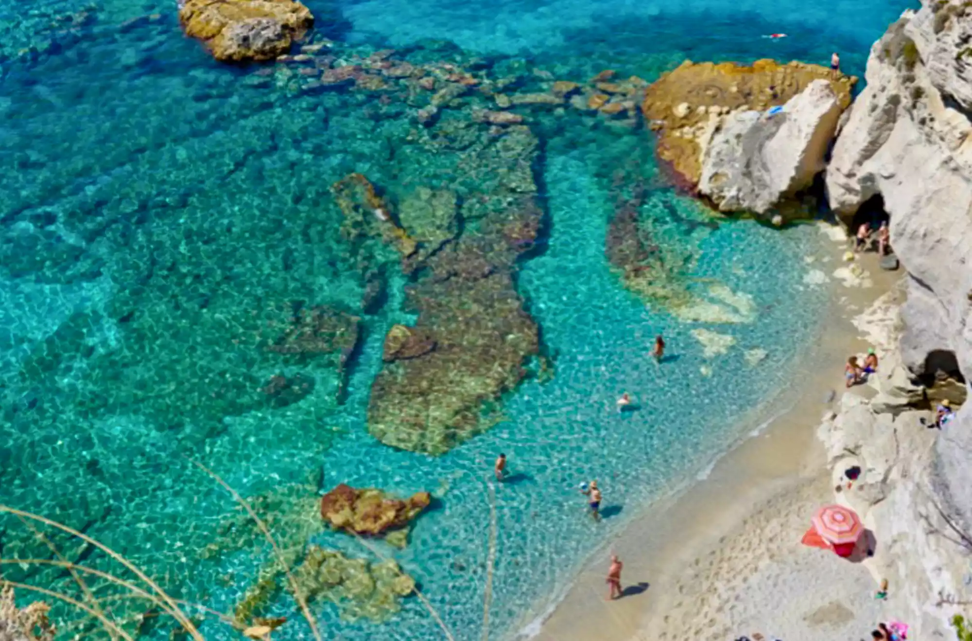 Caletta rocciosa della Costa degli Dei in Calabria con acqua cristallina e fondali visibili.