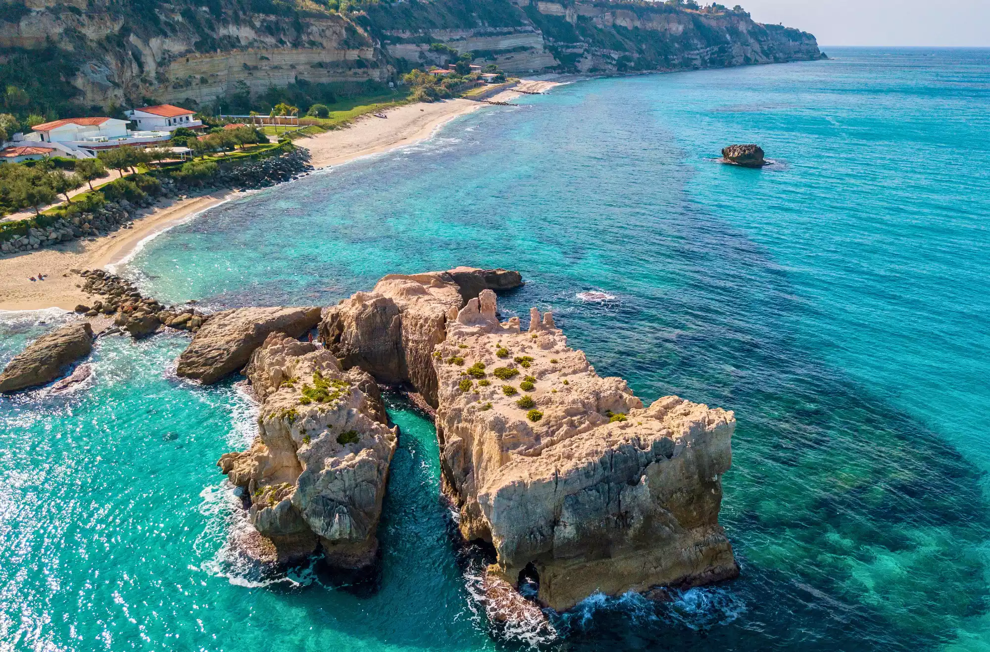 Baia di Riaci, tra Tropea e Santa Domenica di Ricadi – Spiaggia di sabbia chiara con fondali trasparenti, ideale per snorkeling. Famosa per lo Scoglio Grande, simbolo naturale della zona, e per il contrasto tra rocce e mare cristallino.