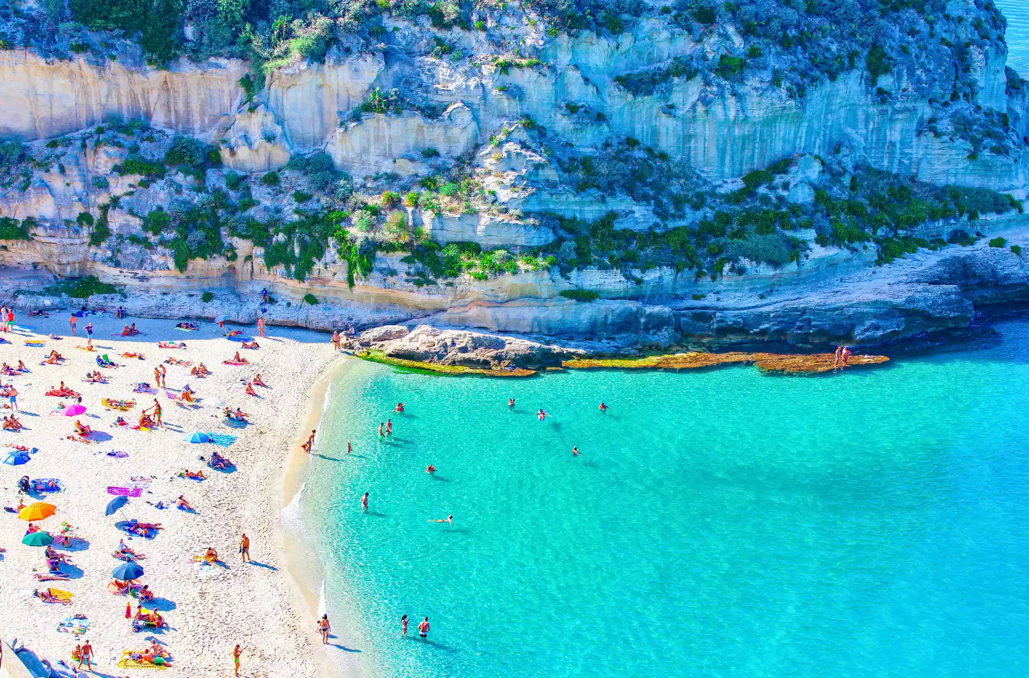 Spiaggia bianca con mare turchese a Tropea vicino Capo Vaticano, Calabria, affollata di turisti in estate